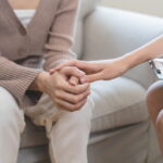 Counselor holding a client's hands during a 7-OH addiction treatment session